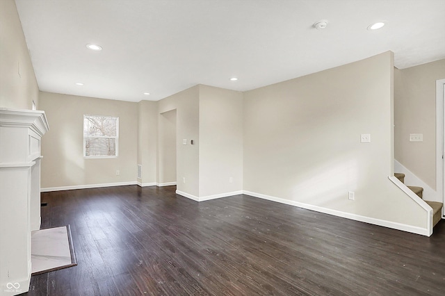 unfurnished living room with baseboards, stairway, dark wood-style flooring, and recessed lighting