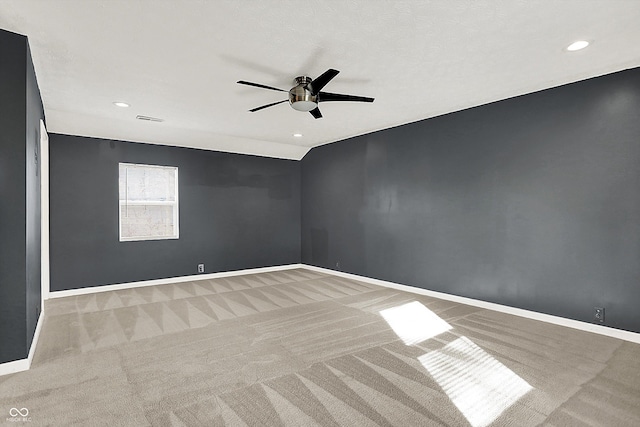 empty room featuring carpet flooring, vaulted ceiling, visible vents, and baseboards