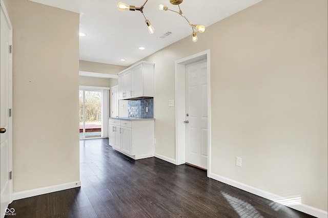 kitchen featuring tasteful backsplash, baseboards, dark wood-type flooring, light countertops, and white cabinetry