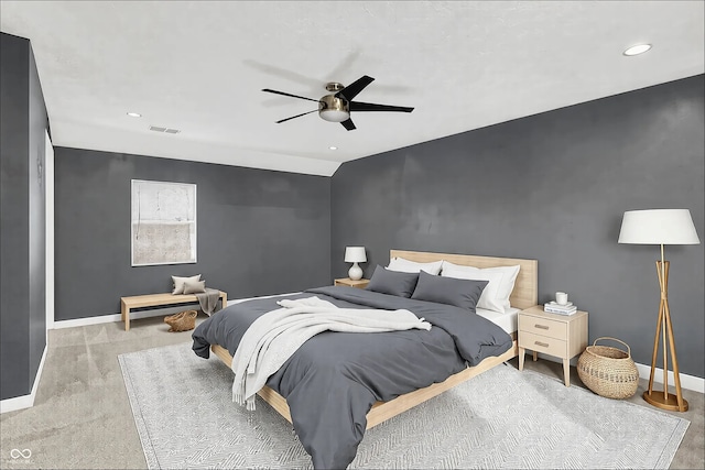 carpeted bedroom featuring baseboards, an accent wall, visible vents, and ceiling fan