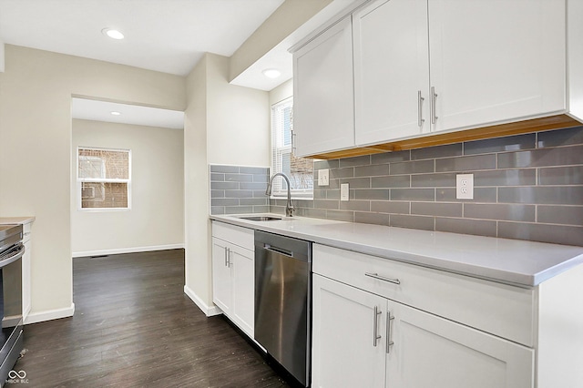 kitchen with a sink, light countertops, appliances with stainless steel finishes, dark wood-style floors, and tasteful backsplash