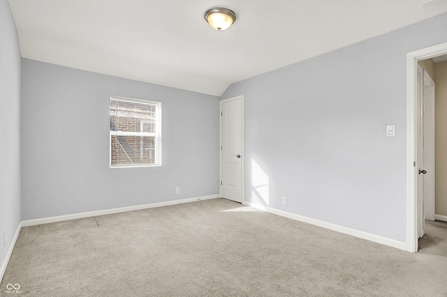 carpeted empty room with vaulted ceiling, visible vents, and baseboards