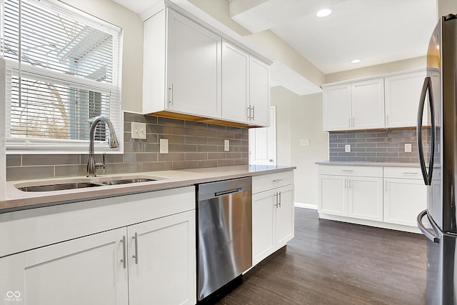 kitchen featuring white cabinets, appliances with stainless steel finishes, dark wood-type flooring, light countertops, and a sink