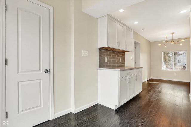 kitchen featuring white cabinetry, baseboards, dark wood finished floors, and decorative backsplash