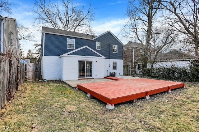 back of property featuring brick siding, a fenced backyard, a lawn, and a wooden deck