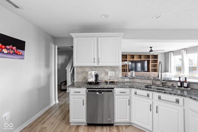 kitchen featuring stainless steel dishwasher, dark stone counters, sink, and white cabinets