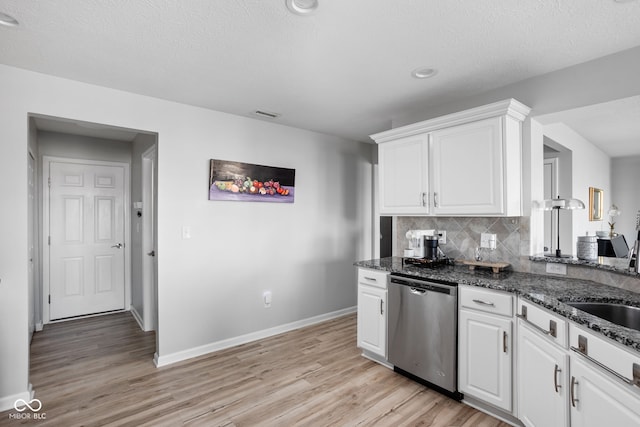 kitchen featuring white cabinetry, decorative backsplash, stainless steel dishwasher, and dark stone counters