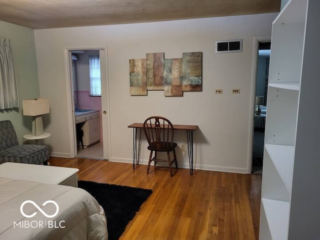 bedroom with hardwood / wood-style flooring and connected bathroom