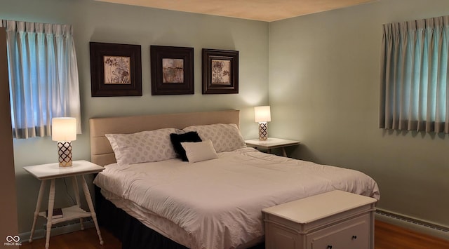 bedroom with dark hardwood / wood-style flooring and baseboard heating