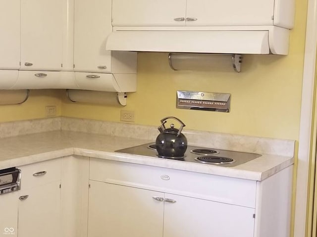 kitchen with white cabinetry, black electric stovetop, and range hood