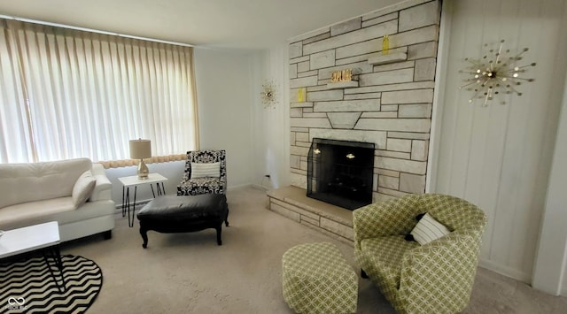 carpeted living room with a stone fireplace