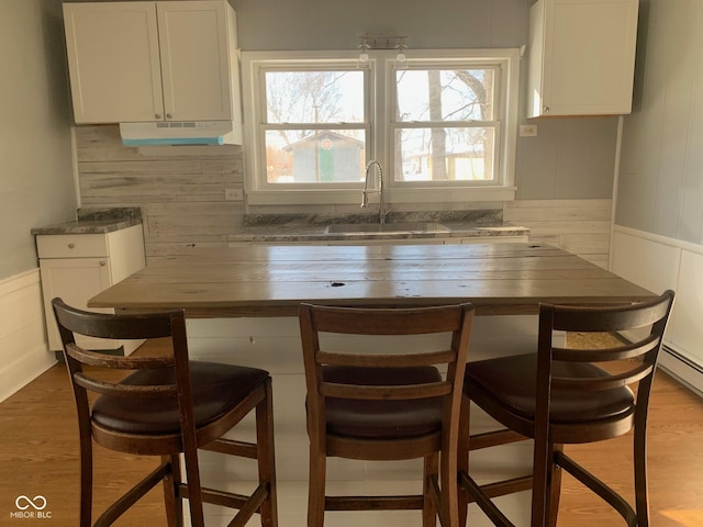 bar featuring sink, a wealth of natural light, hardwood / wood-style floors, and white cabinets