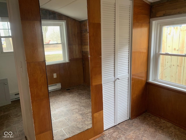 hall featuring wooden walls, a baseboard radiator, and vaulted ceiling