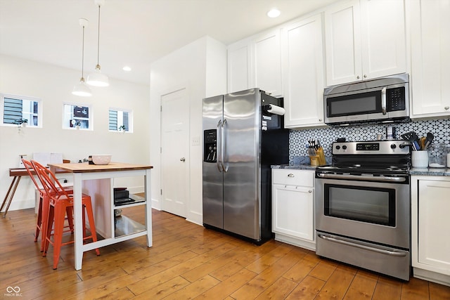 kitchen with pendant lighting, backsplash, white cabinetry, and stainless steel appliances