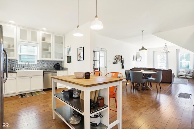 kitchen with pendant lighting, dark wood-type flooring, stainless steel dishwasher, and white cabinets