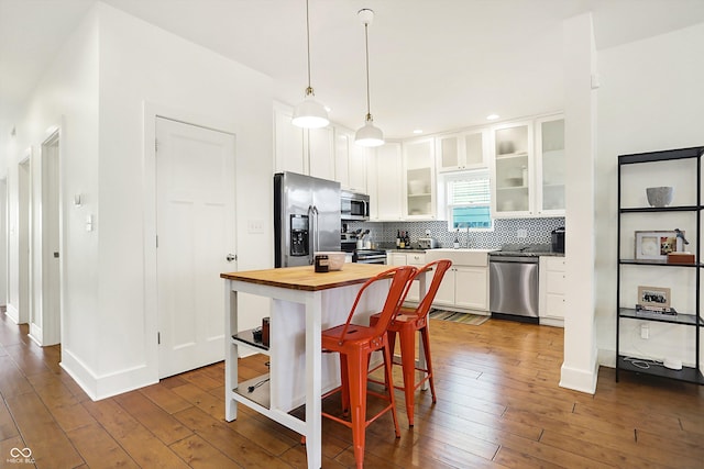 kitchen featuring white cabinetry, appliances with stainless steel finishes, dark hardwood / wood-style flooring, pendant lighting, and backsplash