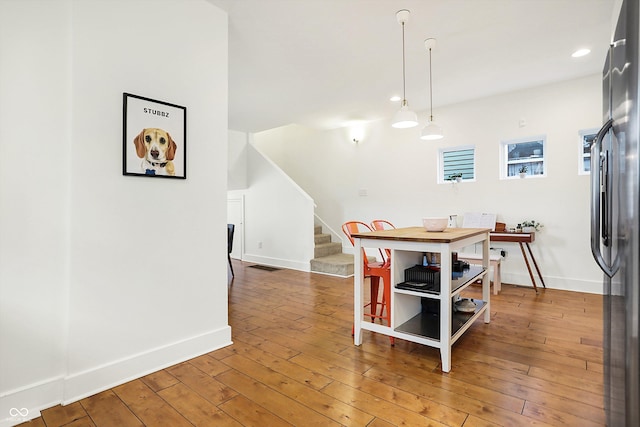 kitchen featuring hardwood / wood-style flooring, stainless steel fridge, and decorative light fixtures