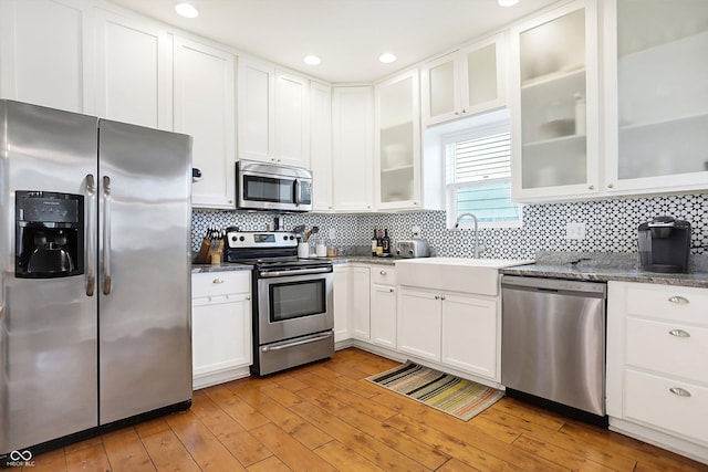 kitchen featuring sink, light wood-type flooring, appliances with stainless steel finishes, decorative backsplash, and white cabinets