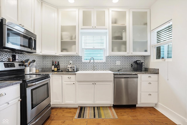 kitchen featuring white cabinetry, decorative backsplash, stainless steel appliances, and dark stone countertops