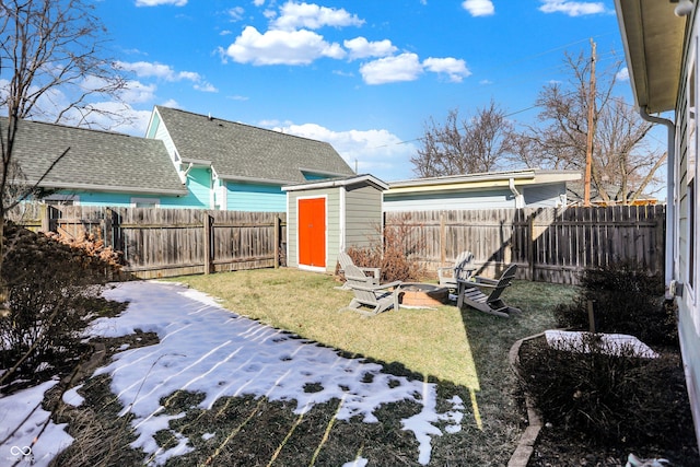 snowy yard with a storage shed and a fire pit