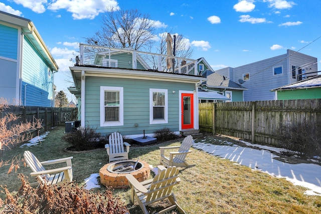 rear view of property featuring cooling unit, a fire pit, a lawn, and a balcony