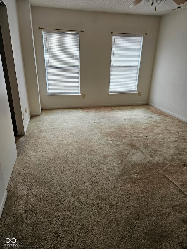 empty room with ceiling fan, carpet flooring, and a textured ceiling