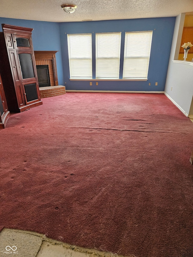 unfurnished living room with a fireplace, carpet, and a textured ceiling