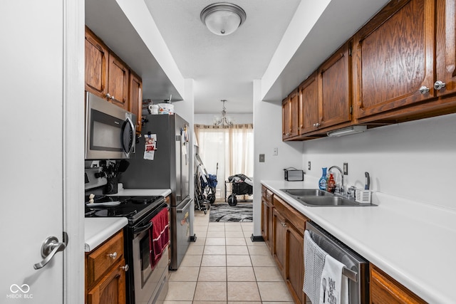 kitchen with pendant lighting, sink, appliances with stainless steel finishes, an inviting chandelier, and light tile patterned flooring