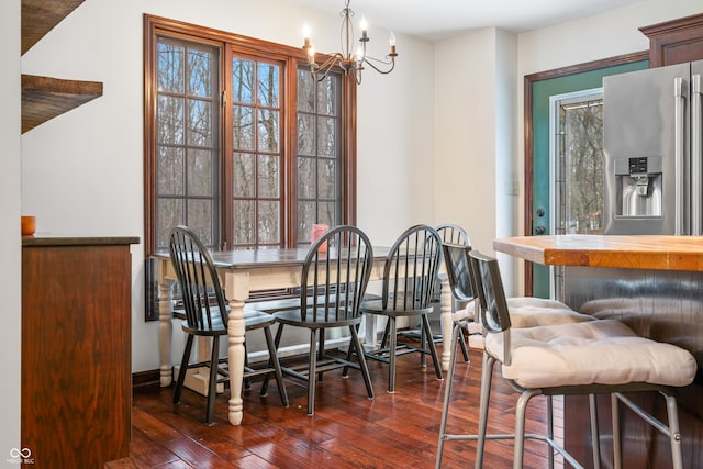 dining space with dark wood-type flooring, bar, and a notable chandelier