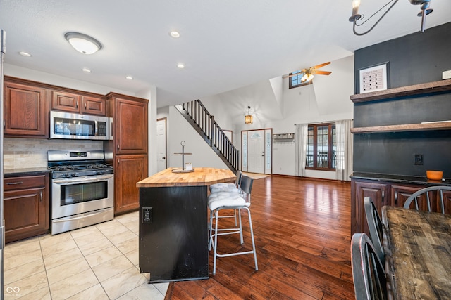 kitchen featuring wooden counters, a kitchen breakfast bar, stainless steel appliances, a kitchen island, and decorative backsplash