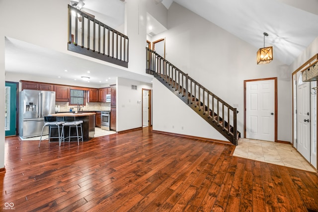 entrance foyer featuring sink, a chandelier, high vaulted ceiling, and light hardwood / wood-style flooring