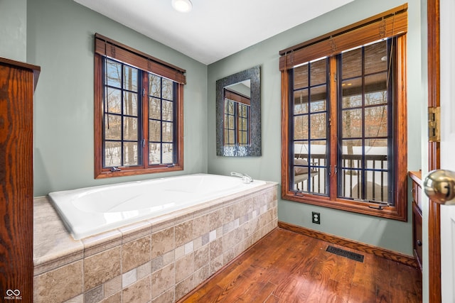 bathroom with hardwood / wood-style flooring and tiled bath