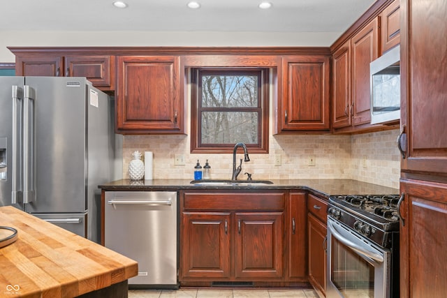 kitchen with dark stone countertops, sink, decorative backsplash, and stainless steel appliances