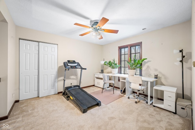 exercise area featuring ceiling fan, light colored carpet, and a textured ceiling