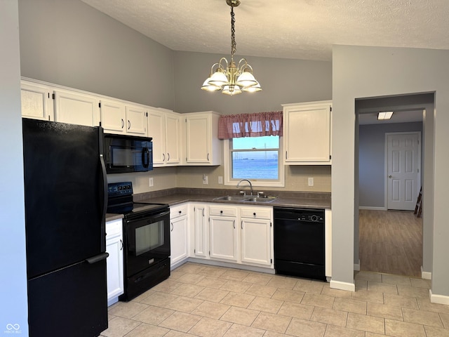 kitchen featuring sink, black appliances, white cabinets, decorative light fixtures, and a chandelier