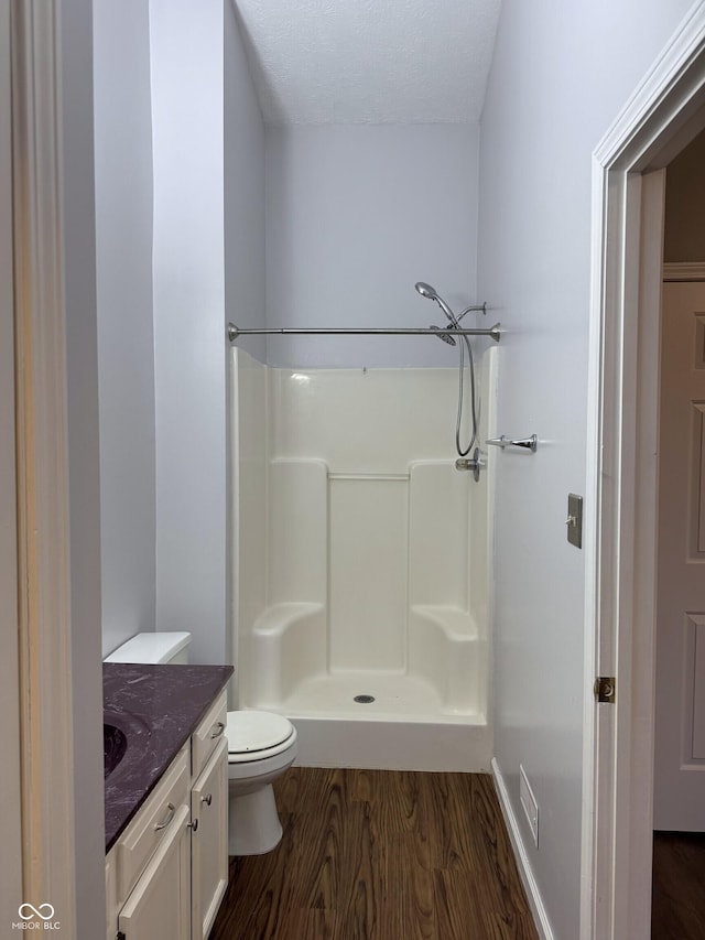 bathroom with a shower, hardwood / wood-style floors, vanity, and toilet