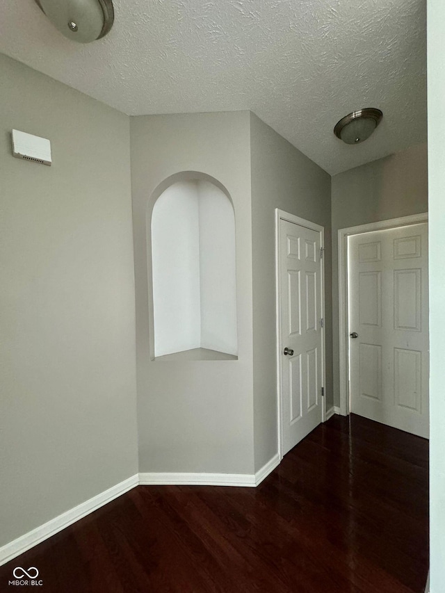 hall with dark hardwood / wood-style floors and a textured ceiling