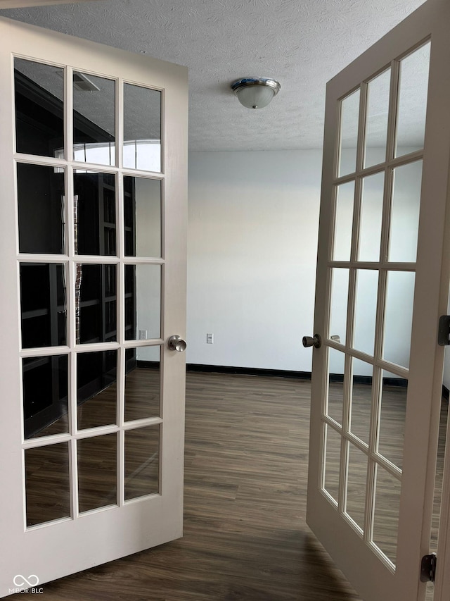 hall with french doors, dark wood-type flooring, and a textured ceiling