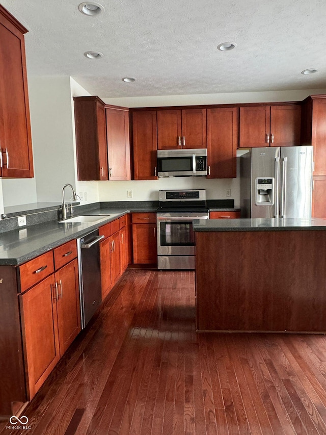 kitchen featuring stainless steel appliances, sink, dark wood-type flooring, and a textured ceiling