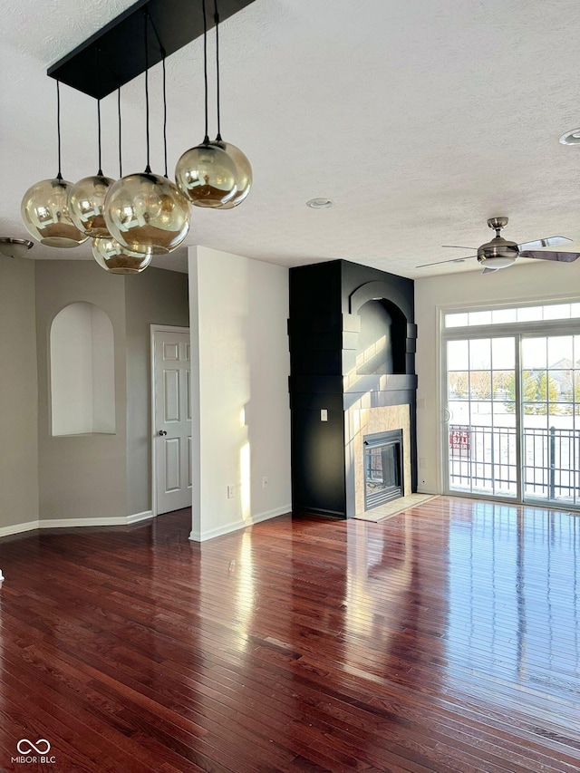 unfurnished living room featuring hardwood / wood-style floors, a textured ceiling, a fireplace, and ceiling fan