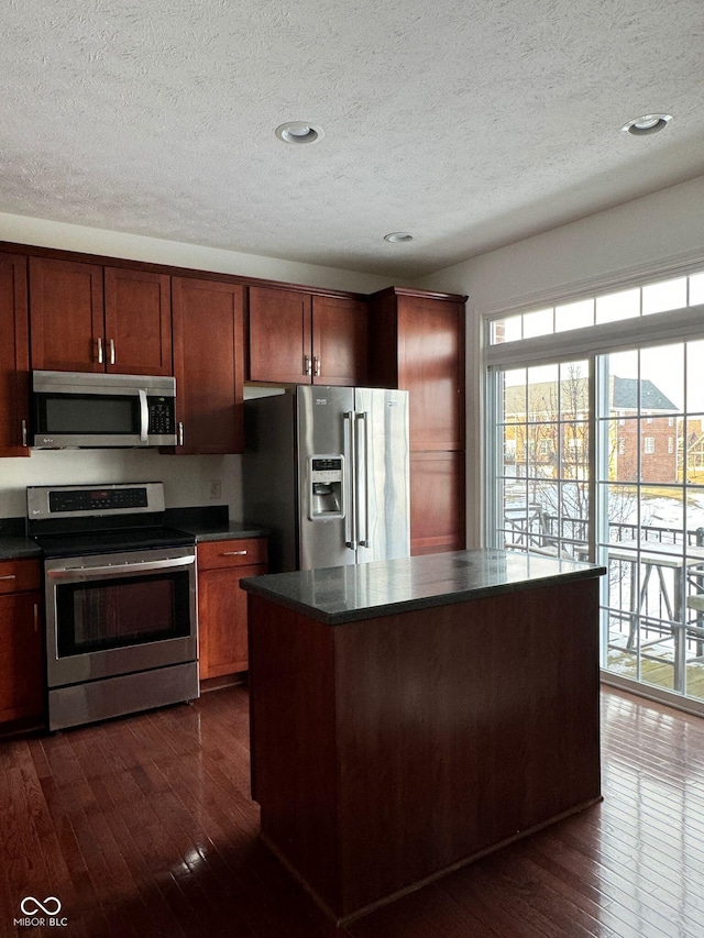 kitchen with a kitchen island, appliances with stainless steel finishes, dark hardwood / wood-style flooring, and a textured ceiling