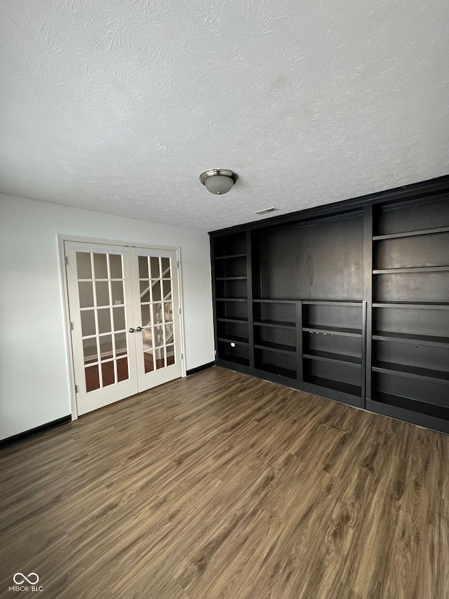 unfurnished bedroom with dark wood-type flooring, french doors, and a textured ceiling