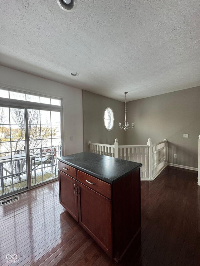 kitchen with pendant lighting, plenty of natural light, dark hardwood / wood-style floors, and a kitchen island