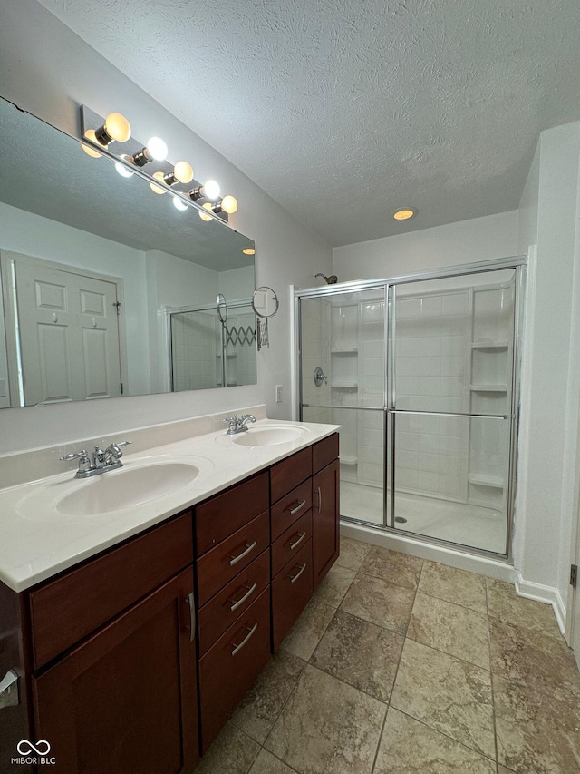 bathroom with vanity, a textured ceiling, and walk in shower