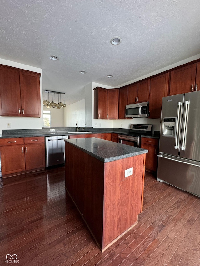 kitchen with dark hardwood / wood-style floors, a center island, kitchen peninsula, stainless steel appliances, and a textured ceiling