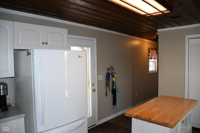 kitchen with butcher block counters, wood ceiling, white cabinets, and white fridge