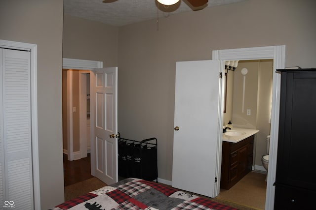 bedroom featuring ensuite bath, sink, and a textured ceiling