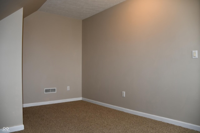 unfurnished room with vaulted ceiling, a textured ceiling, and carpet