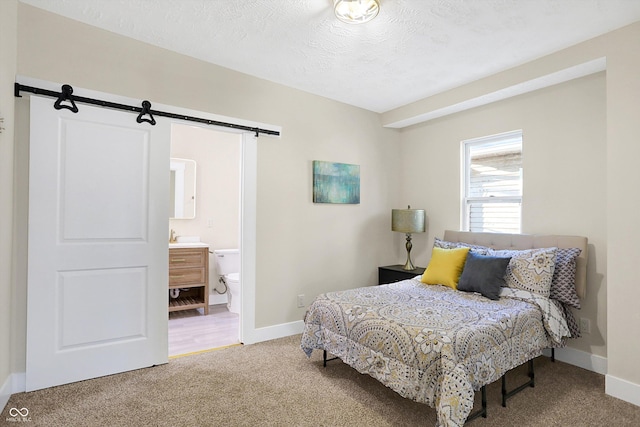 carpeted bedroom featuring a barn door, connected bathroom, and a textured ceiling