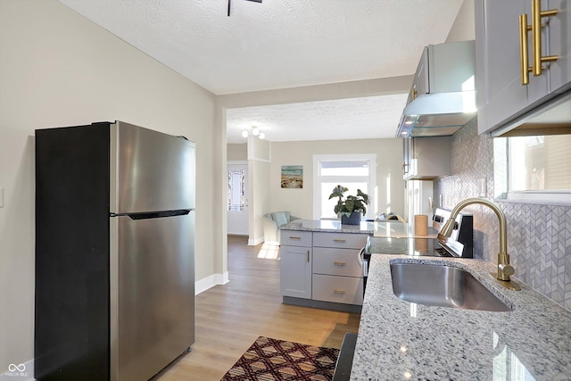 kitchen featuring gray cabinets, light stone countertops, sink, and stainless steel refrigerator